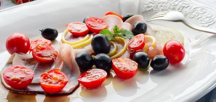 Carpaccio di pesce spada con olive nere, pomodorini e scorze di limone
